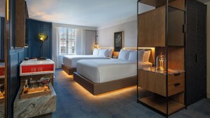 A hotel room with a large bed, a desk with a lamp, a wardrobe, and a view of the city through the window. - Hotel de la Poste – French Quarter, A Renaissance Hotel (New Orleans)