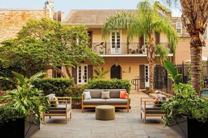 Un patio con un sofá, dos sillones y un otoman redonda.