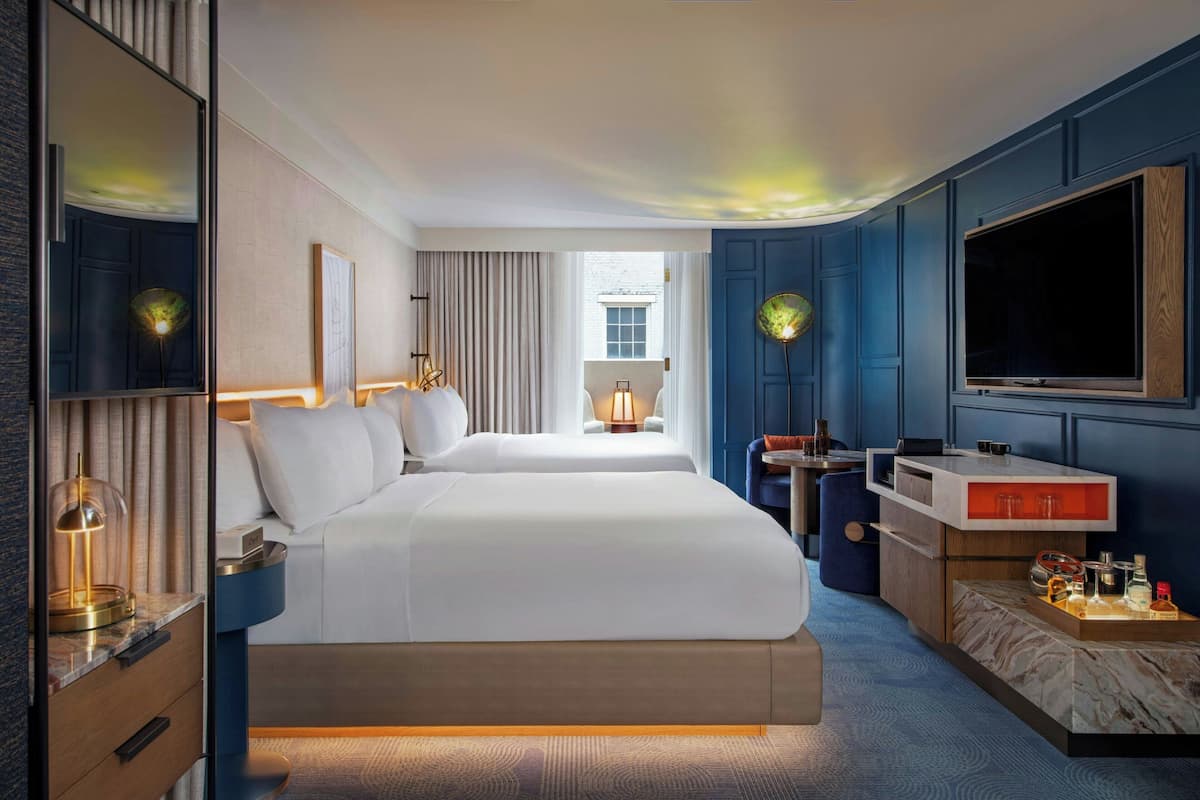 A hotel room with a large bed, a desk with a TV, and a view of the city.