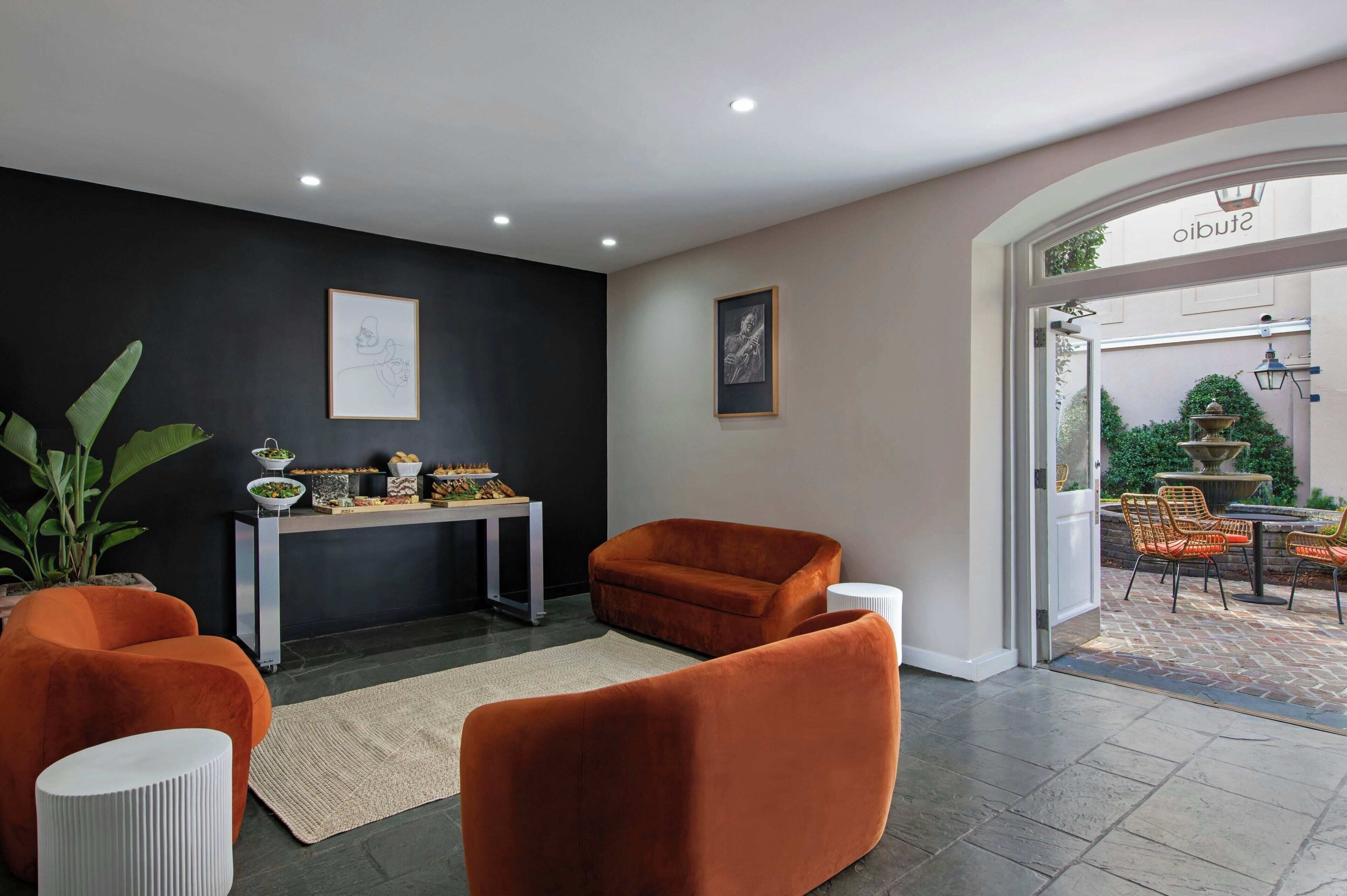 Un interior moderno con una pared de acento negra, un mostrador de recepción y vistas al patio exterior.