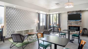 Un espace repas moderne avec un mur en pierre, de grandes fenêtres et un téléviseur à écran plat.