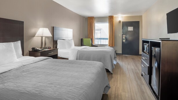 A hotel room with two beds, a desk, a lamp, a television, and a minibar. - Quality Inn Simpsonville - Greenville (Simpsonville)