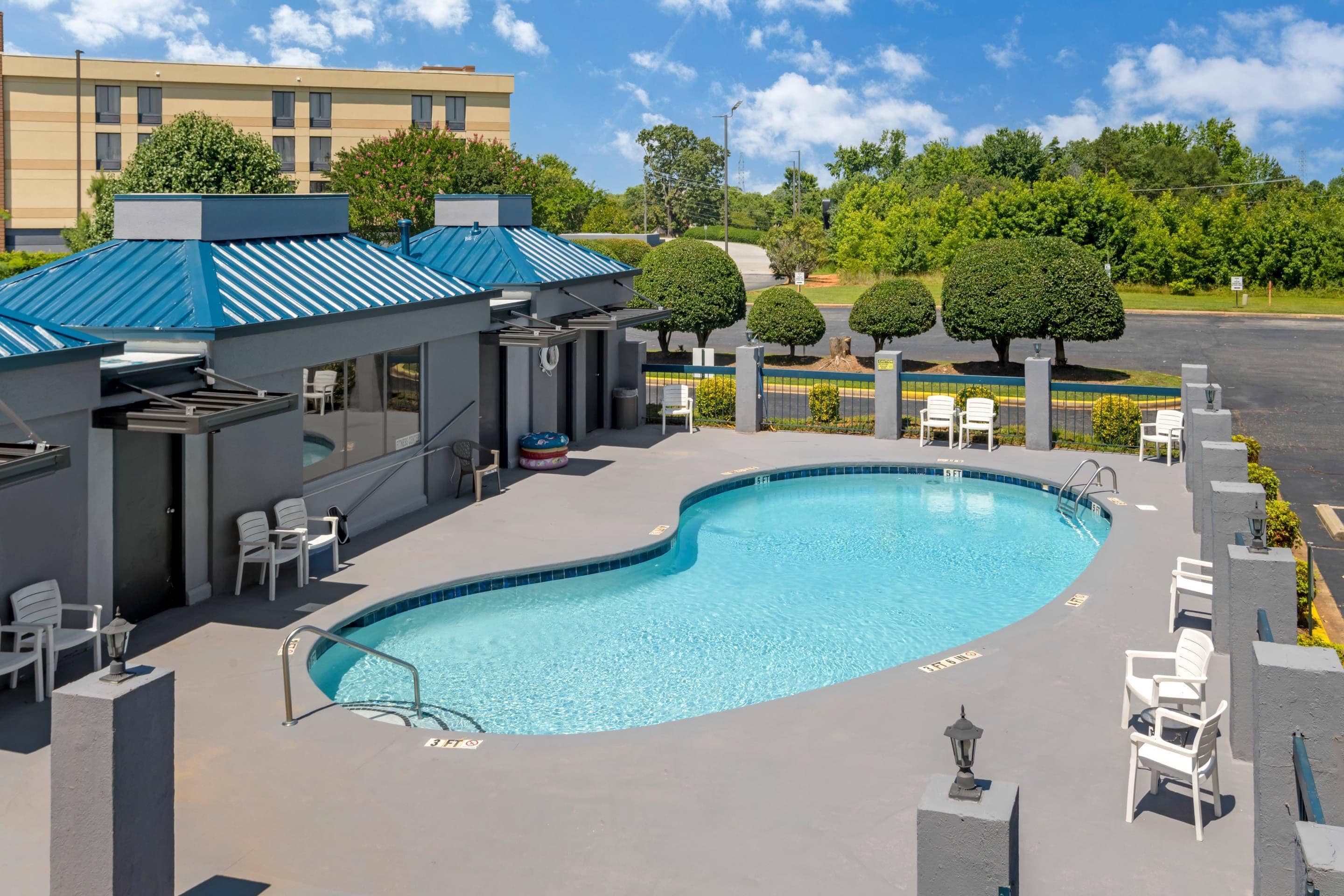 A swimming pool with lounge chairs and a covered area with a blue roof.