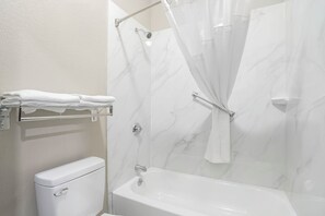 A bathroom with a white toilet, a bathtub, and a shower with a glass door. - Quality Inn Simpsonville - Greenville (Simpsonville)