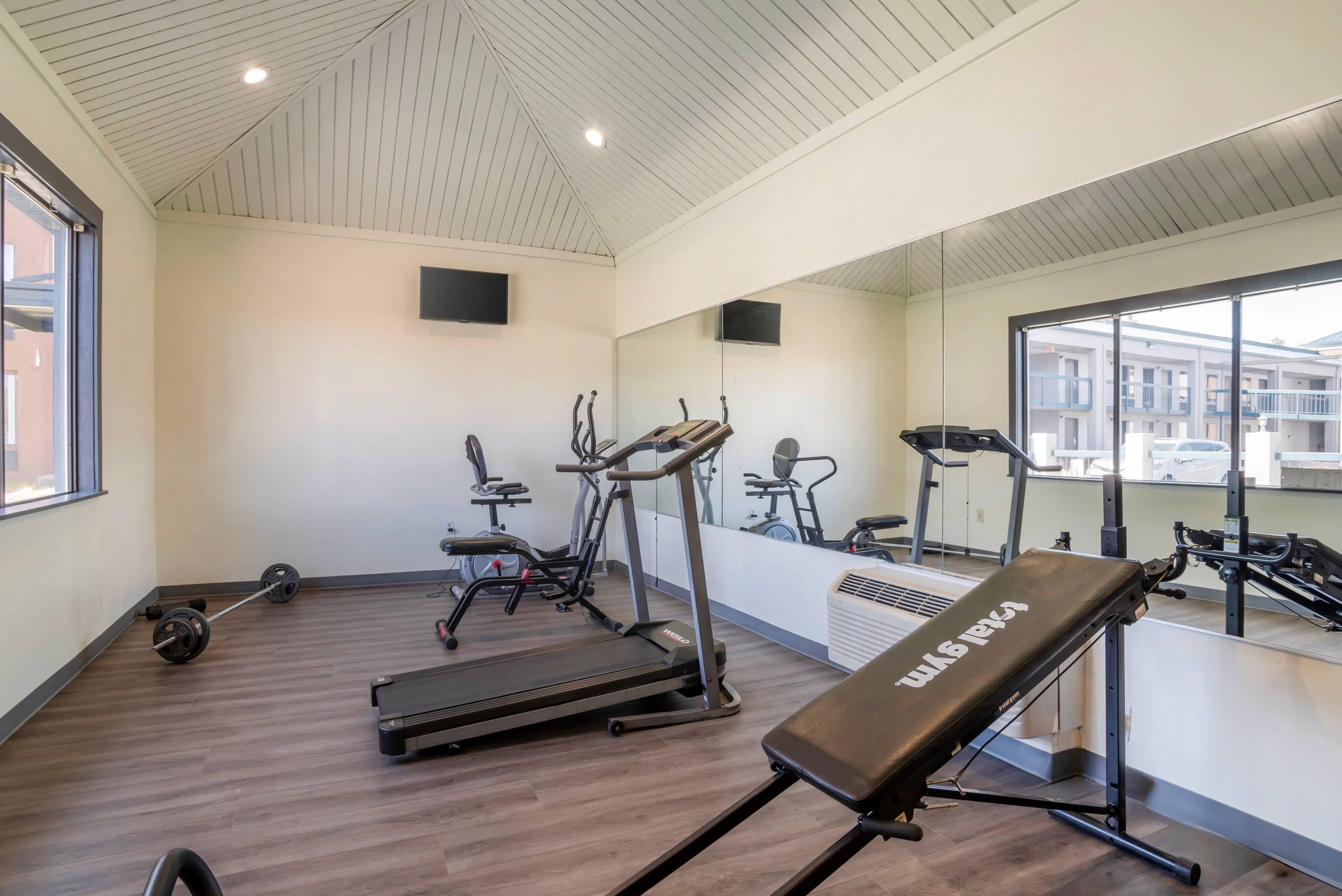 Une salle de sport équipée de tapis de course, d’un banc et de matériel de musculation.