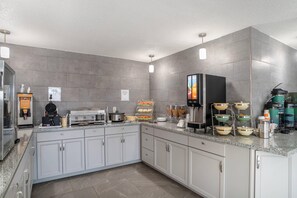 A modern kitchen with a waffle maker, coffee machine, and breakfast bar. - Quality Inn Simpsonville - Greenville (Simpsonville)