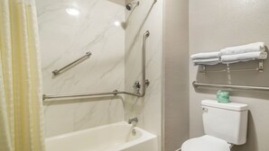 A bathroom with a bathtub, a toilet, and a shower area.