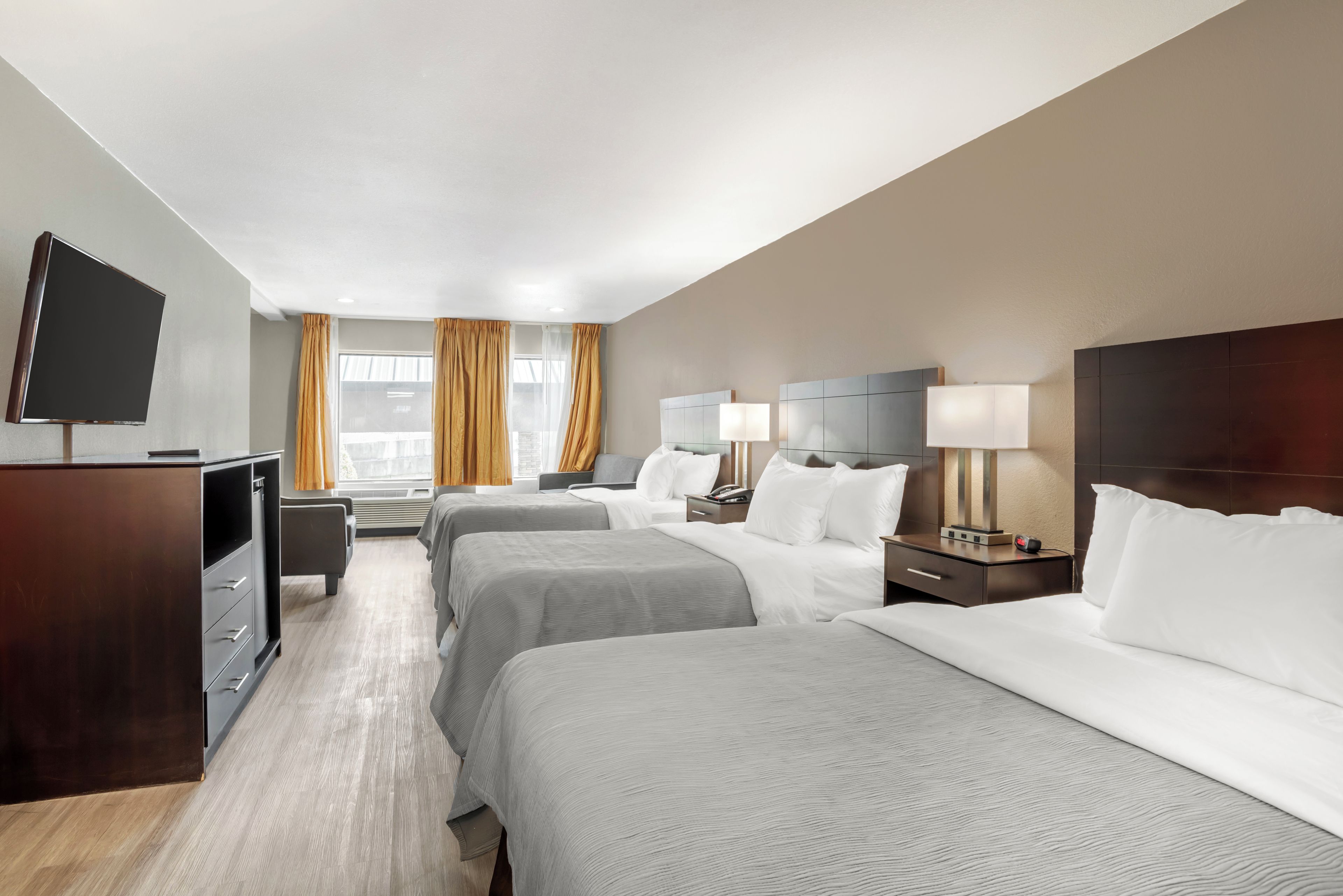 Een hotelkamer met twee bedden, een televisie, een bureau en een raam met gordijnen.