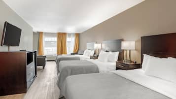 Een hotelkamer met twee bedden, een televisie, een bureau en een raam met gordijnen.