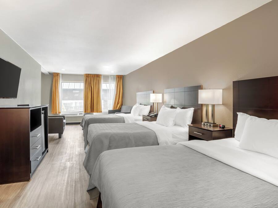 Een hotelkamer met twee bedden, een televisie, een bureau en een raam met gordijnen.