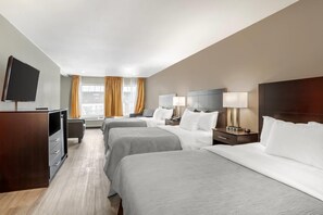 A hotel room with two beds, a desk, a TV, and a window with curtains. - Quality Inn Simpsonville - Greenville (Simpsonville)