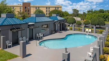 A swimming pool area with a pool, lounge chairs, and a building with a blue roof.