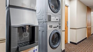 A hotel laundry room with stacked washers and dryers, a water dispenser, and a carpeted hallway. - Super 8 by Wyndham Athens (Athens)