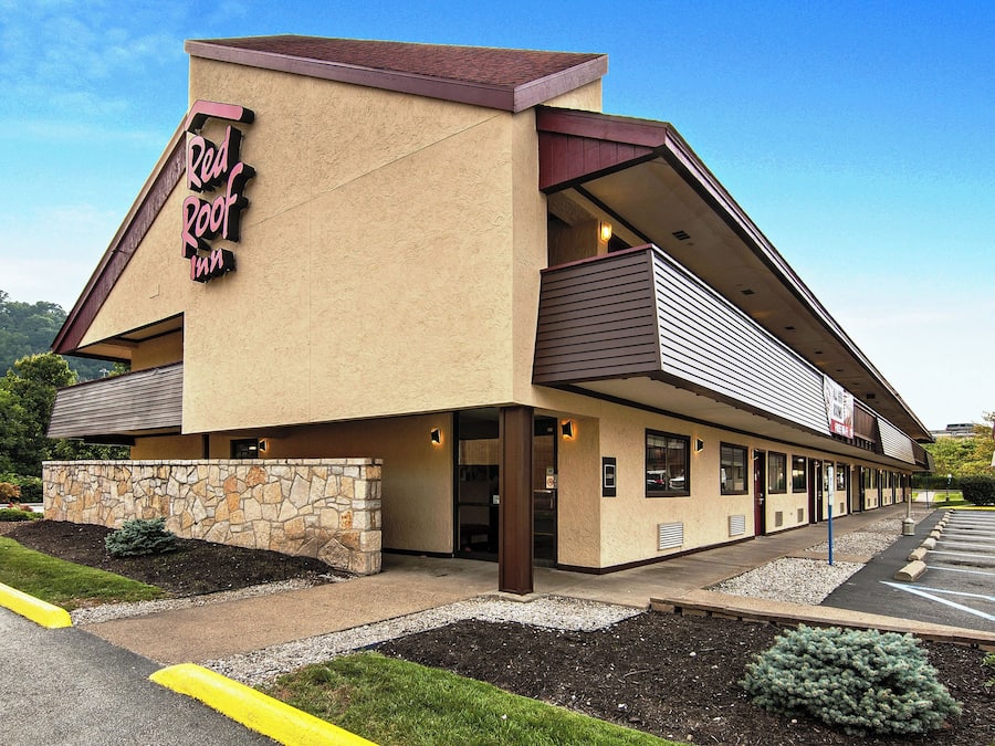 A two-story building with a sign reading 'Root Inn.' It features a stone facade, a parking lot, and a view of a mountain in the background.