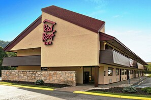 Un Red Roof Inn con fachada de piedra, un edificio de dos pisos y un estacionamiento.