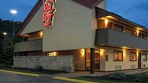 Un Red Roof Inn con fachada de piedra, múltiples ventanas y un letrero de neón.