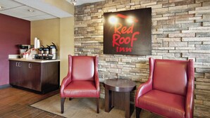 Zona de recepción de Red Roof Inn con pared de piedra, dos sillones de cuero, una mesita y una estación de café.