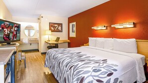 Ein Hotelzimmer mit einem Bett, einem Schreibtisch, einem Stuhl, einem Fernseher und einem Badezimmer.