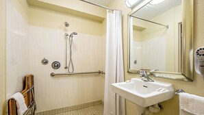 A bathroom with a shower, a sink, a mirror, and a towel rack. - Red Roof Inn Charleston - Kanawha City, WV (Charleston)
