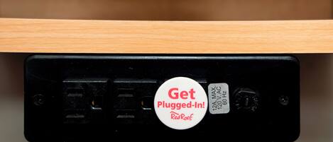Um dispositivo eletrônico preto com um adesivo branco que diz 'Get Plugged-In! RedRoof'.