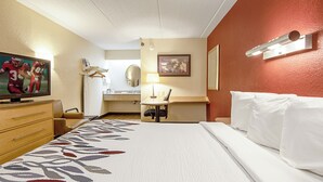 Ein Hotelzimmer mit Bett, Schreibtisch, Stuhl, Fernseher und Badezimmer.