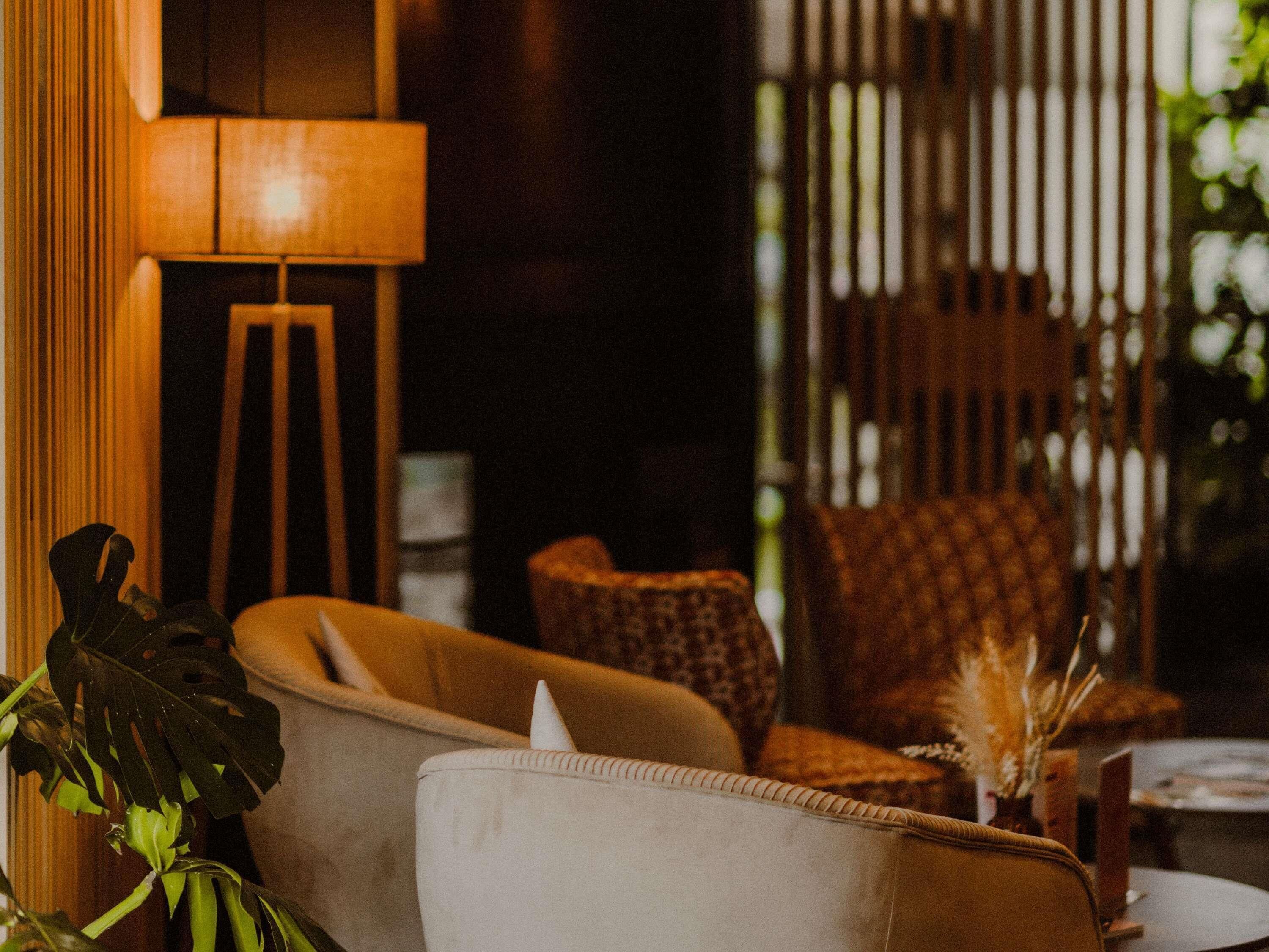 A cozy seating area with a sofa and armchairs, a lamp, and a small table with a vase of dried plants.