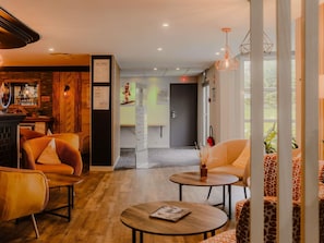 Un vestíbulo de hotel con asientos, una zona de bar y un mostrador de recepción.