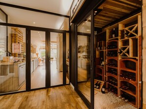 A modern interior with a wine cellar, wooden flooring, and glass doors leading to a dining area. - Mercure Annecy Sud (Annecy)