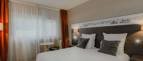 Una habitación de hotel con una cama grande, una mesita pequeña y una silla.