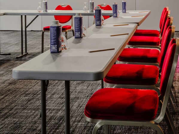 Une salle de conférence équipée de tables, de chaises et de bouteilles dotées de codes QR.