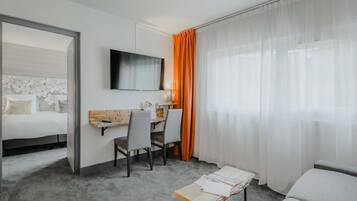 Une chambre d’hôtel avec un lit, un bureau, une télévision et une fenêtre avec des rideaux.