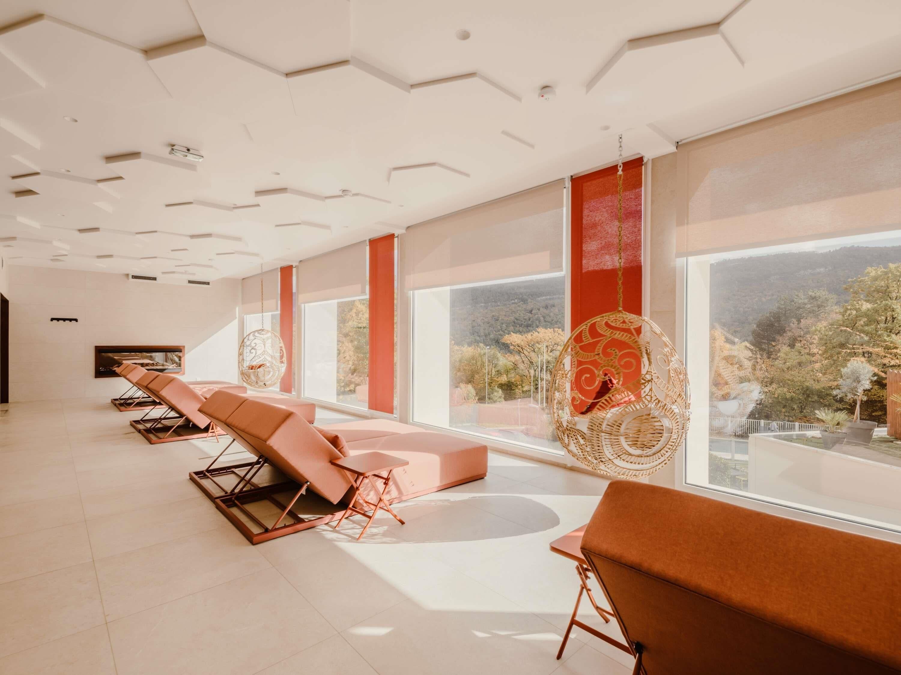 A modern spa room with a large window, a fireplace, and two massage chairs.