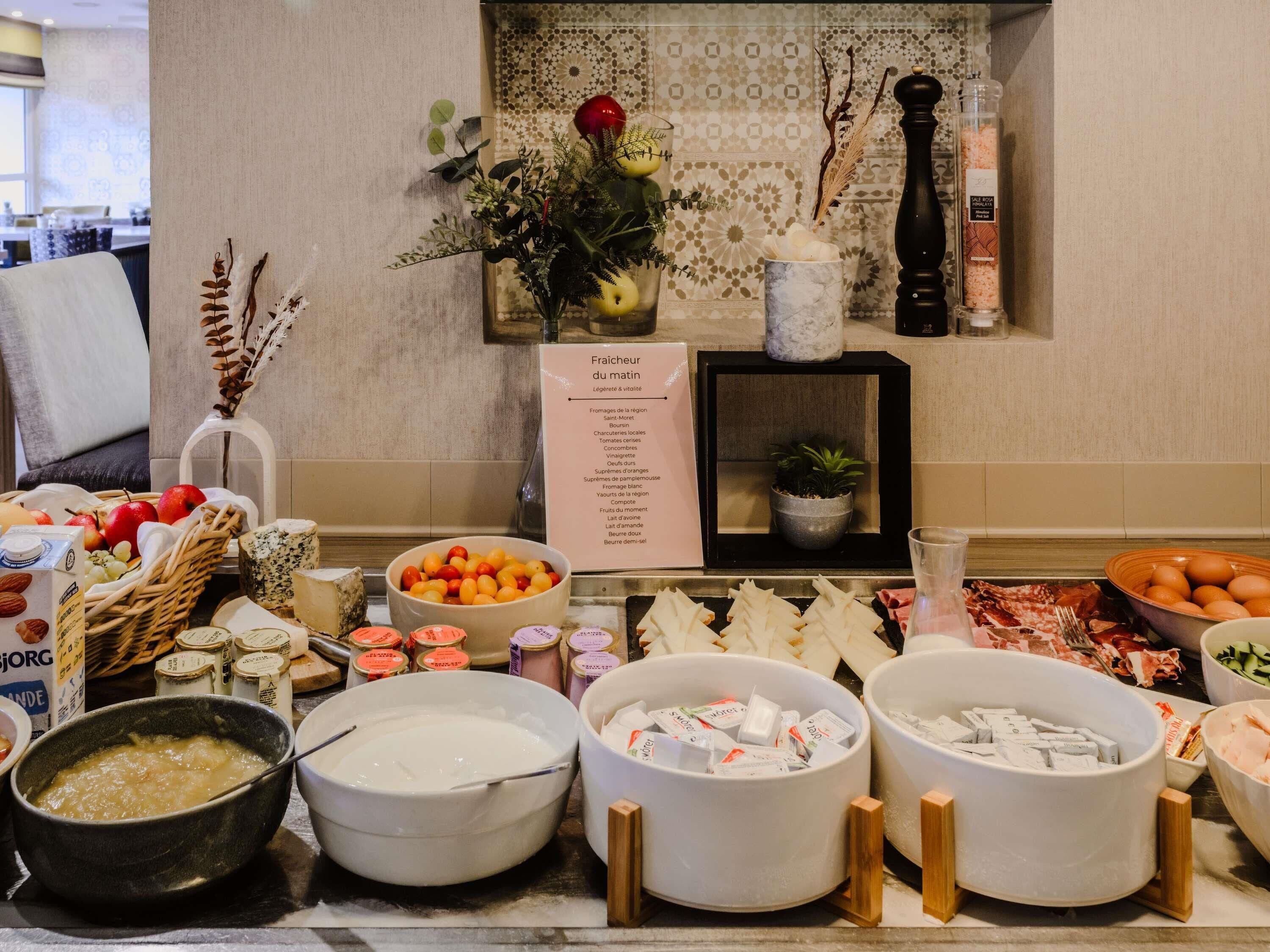 A buffet setup with various food items, a sign listing the menu, and a decorative plant.