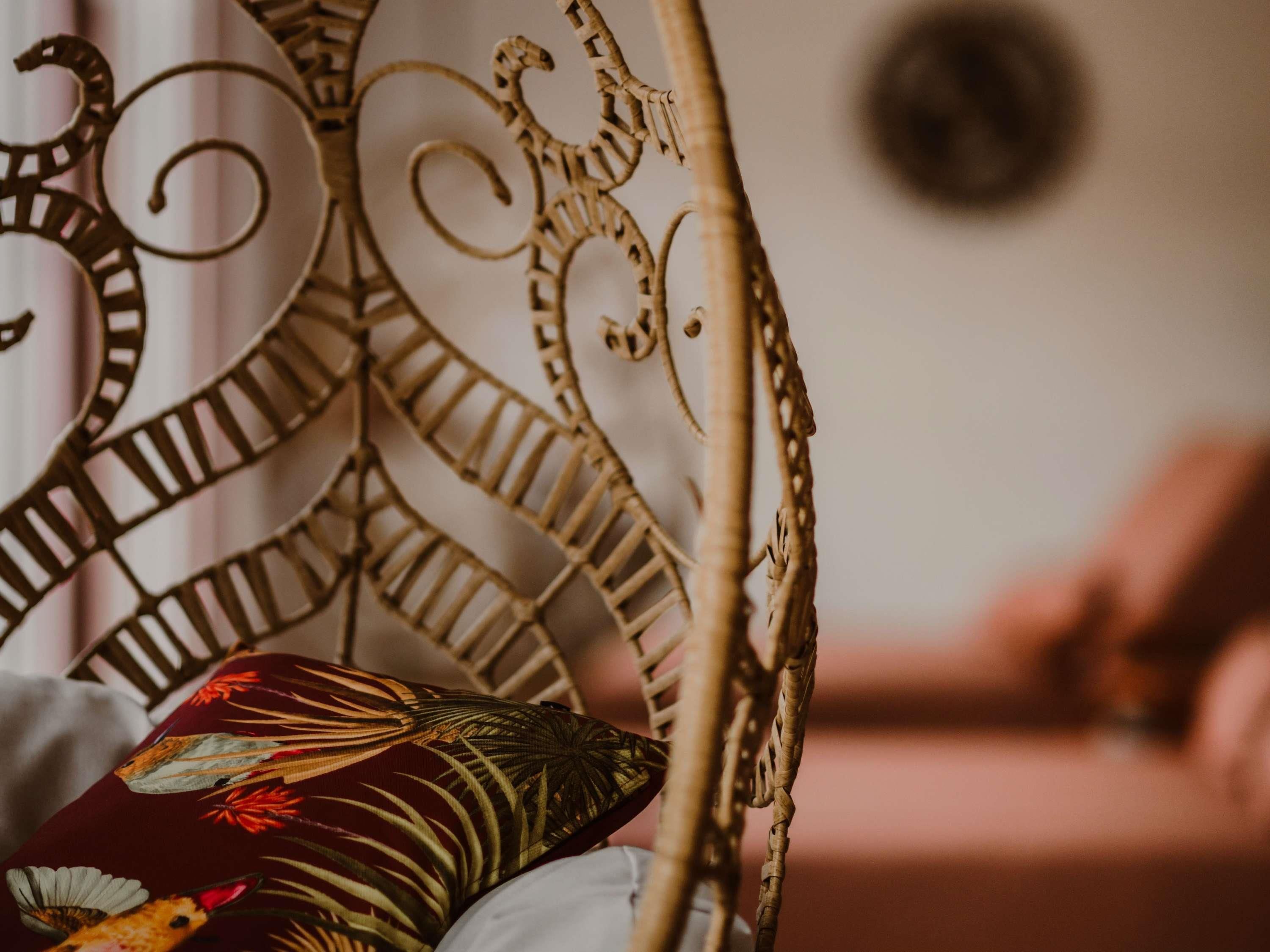 A wicker chair with a decorative backrest and a cushion with a floral pattern.