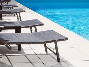 Zona junto a la piscina con sillones de descanso y vista despejada.