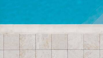 A tiled wall with a pool above.