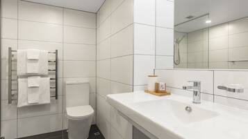 A modern bathroom with a white toilet, a sink with a mirror, and a towel rack.