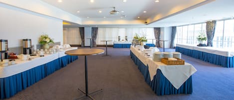 A conference room with long tables, white tablecloths, and blue drapery.