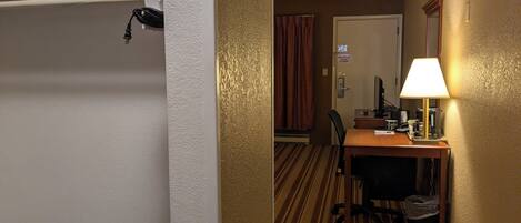 Een hotelkamer met een bed, een bureau met een computer, een lamp en een stoel.