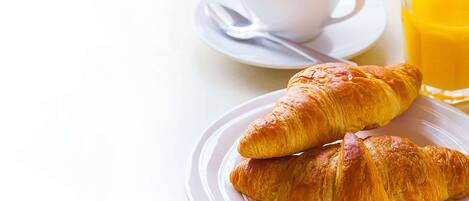 Two croissants on a plate, a cup of coffee, and a glass of orange juice.