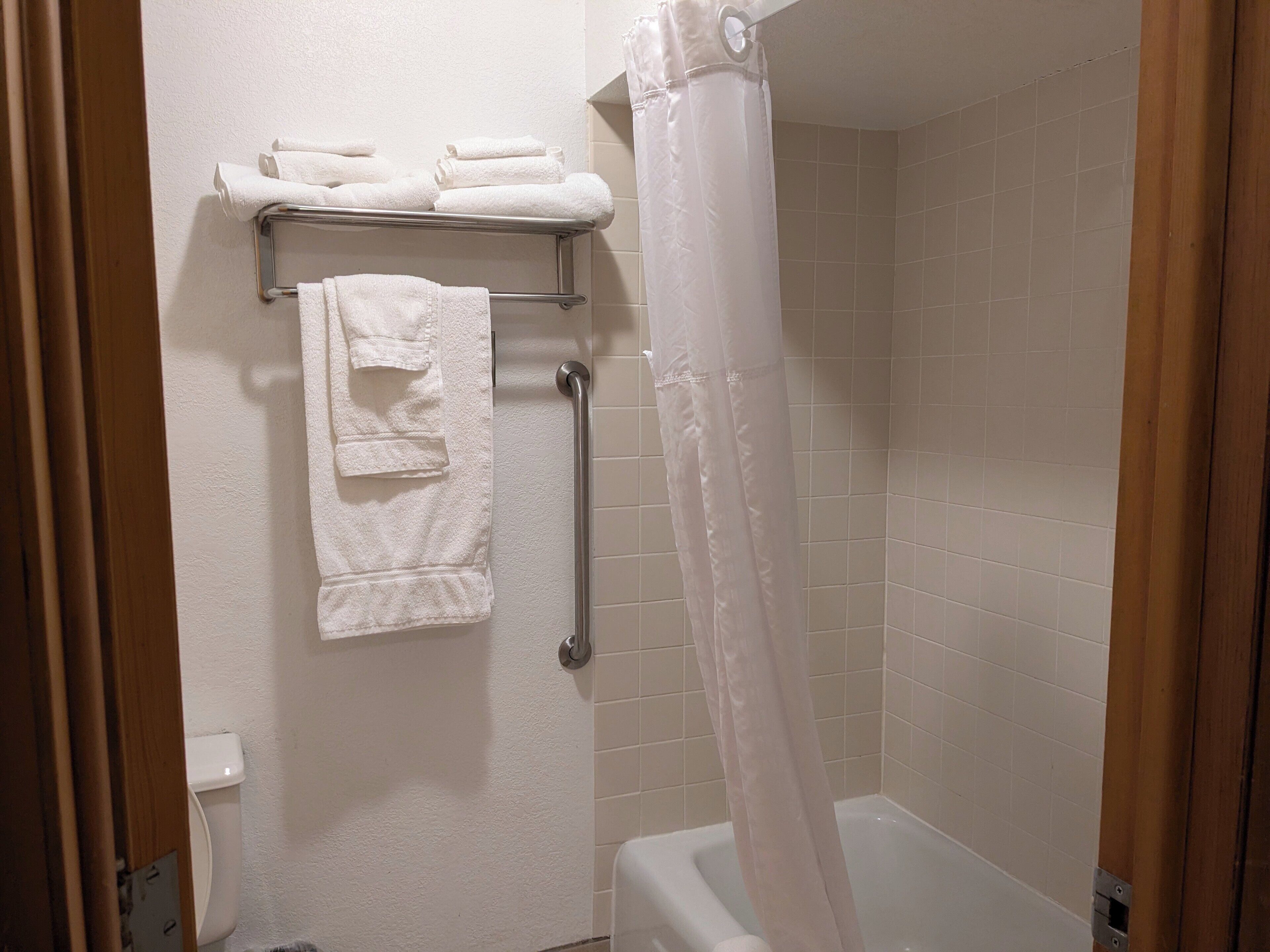 A bathroom with a shower, a toilet, and a towel rack with towels.