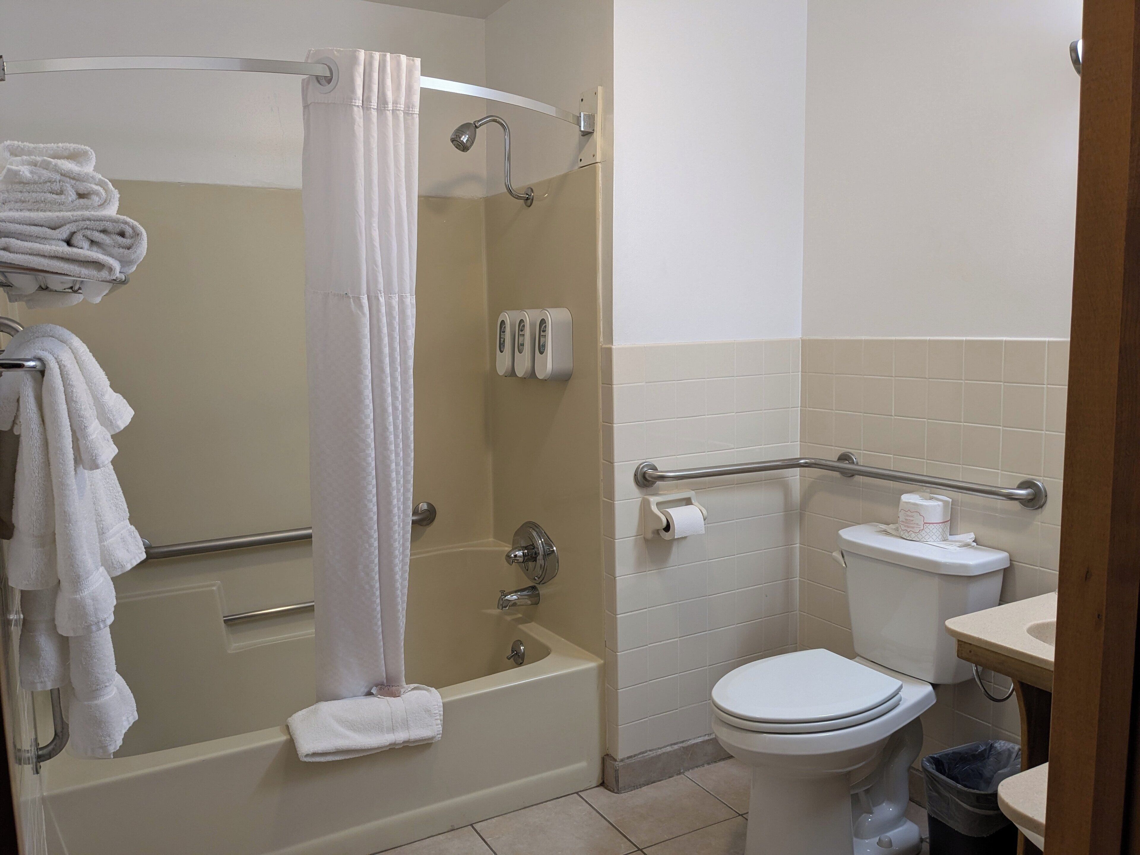 A bathroom with a bathtub, toilet, and hand dryer.
