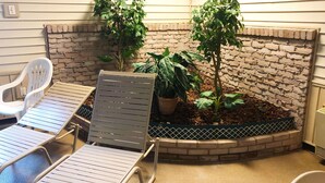 A small outdoor seating area with two lounge chairs and a planter with plants. - Magnuson Hotel Copper Crown (Hancock)
