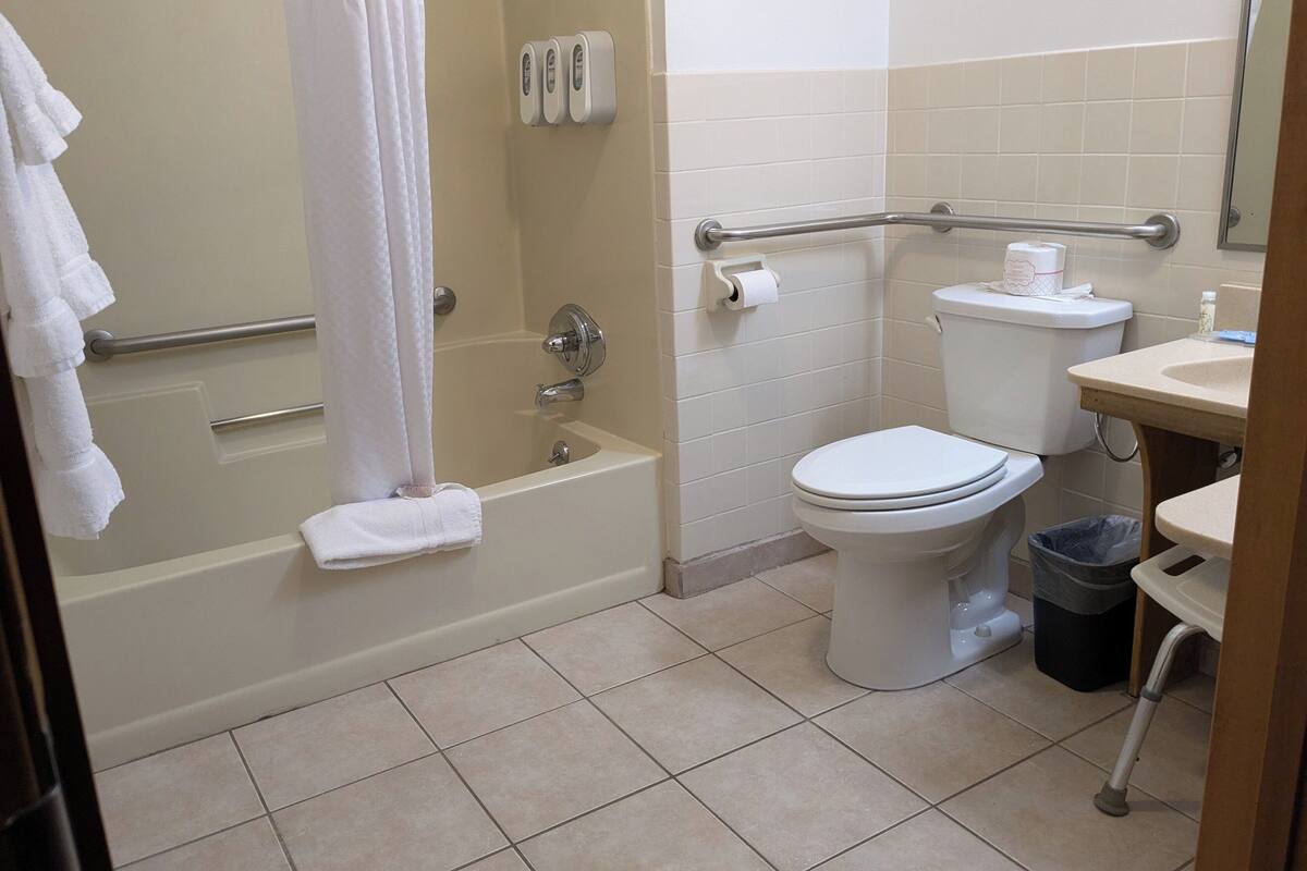 A bathroom with a bathtub, toilet, and hand dryer.