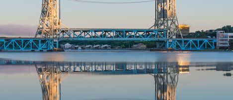 Un puente con su reflejo en el agua, que presenta una estructura azul y dos torres.