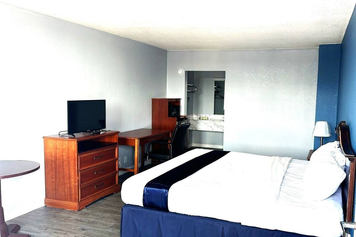 Une chambre d’hôtel équipée d’un lit, d’un bureau, d’une chaise, d’une télévision et d’une petite table.