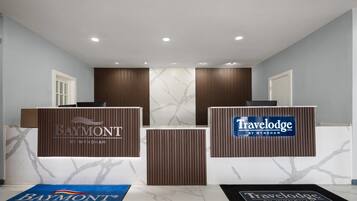 Un área de recepción con dos mostradores identificados como 'Baymont by Wyndham' y 'Travelodge by Wyndham'.
