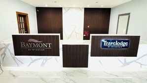 Ein Empfangsbereich mit zwei Empfangstheken, beschriftet mit 'Baymont by Wyndham' und 'Travelodge by Wyndham'.