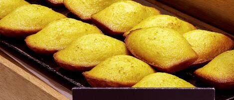 A tray of golden-brown madeleines arranged in a wooden box.