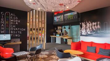 A modern lounge area with a curved ceiling, a reception desk, and a red sofa.